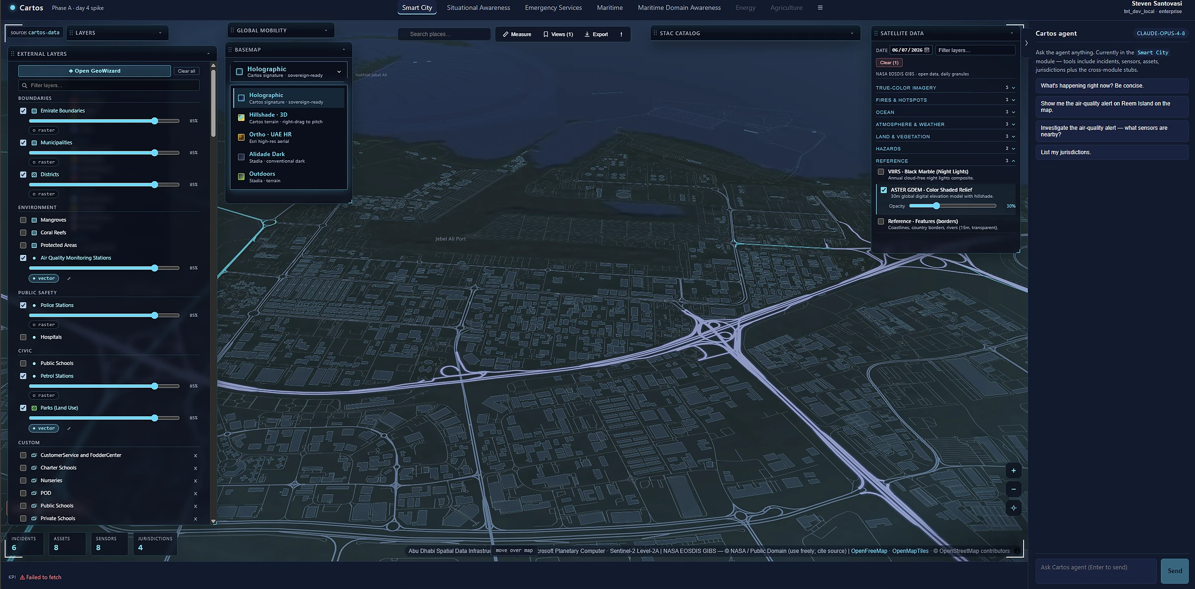 A tilted 3D view of an urban area with extruded buildings, terrain, and a road network in the Cartos globe.